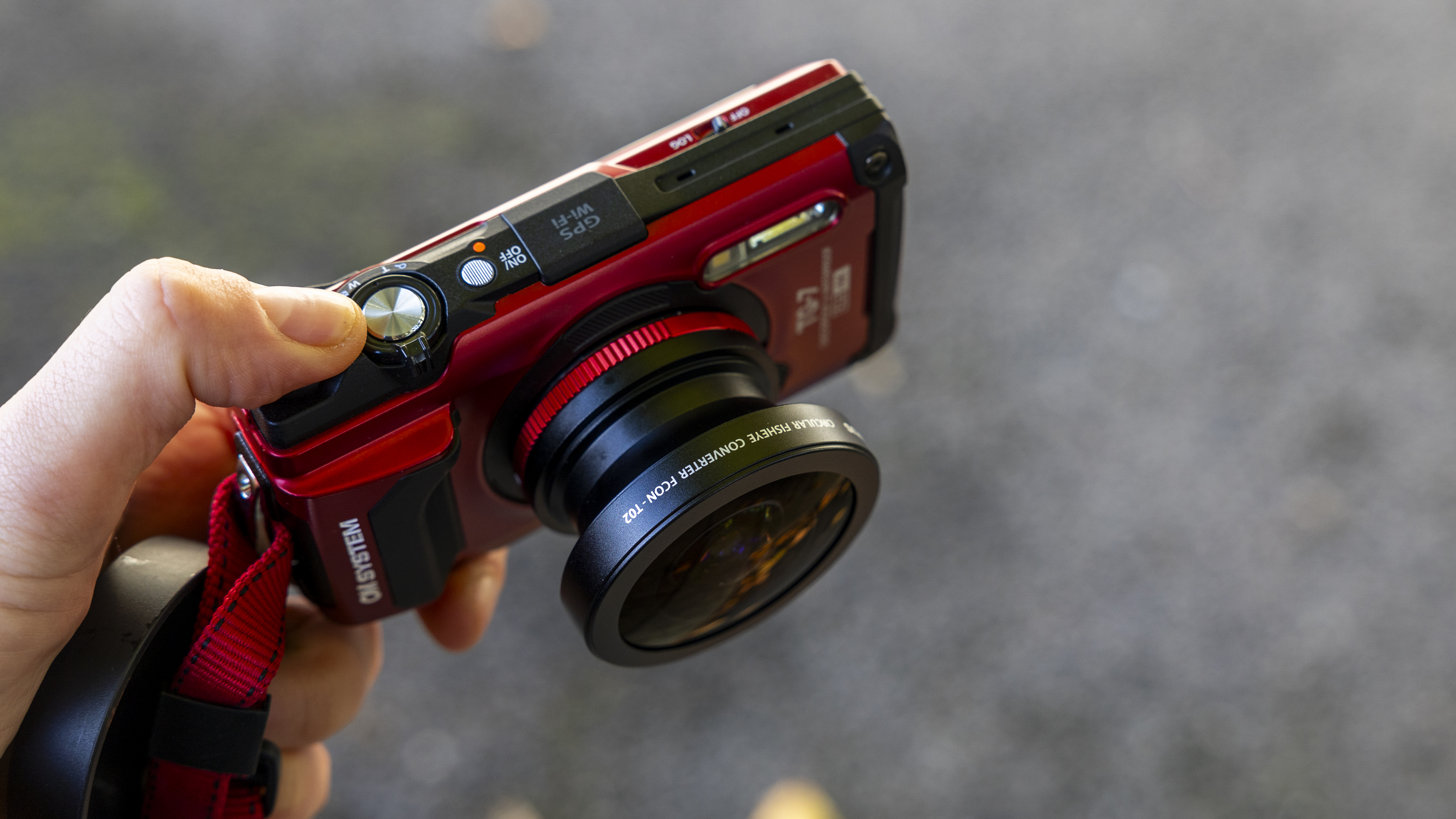 An OM System Tough TG-7 camera fitted with a specialized fisheye lens converter.