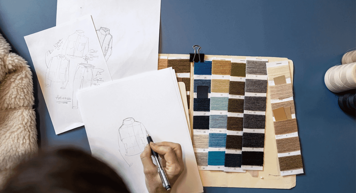 Close-up of a fashion designer sketching a garment prototype with fabric swatches.