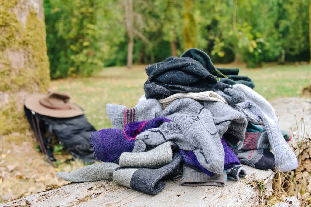 A variety of hiking socks piled together outdoors on a rock for field testing.