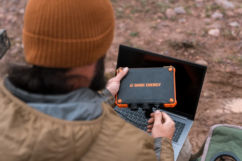 The Dark Energy Poseidon XL connected to a laptop on a wooden surface outdoors.