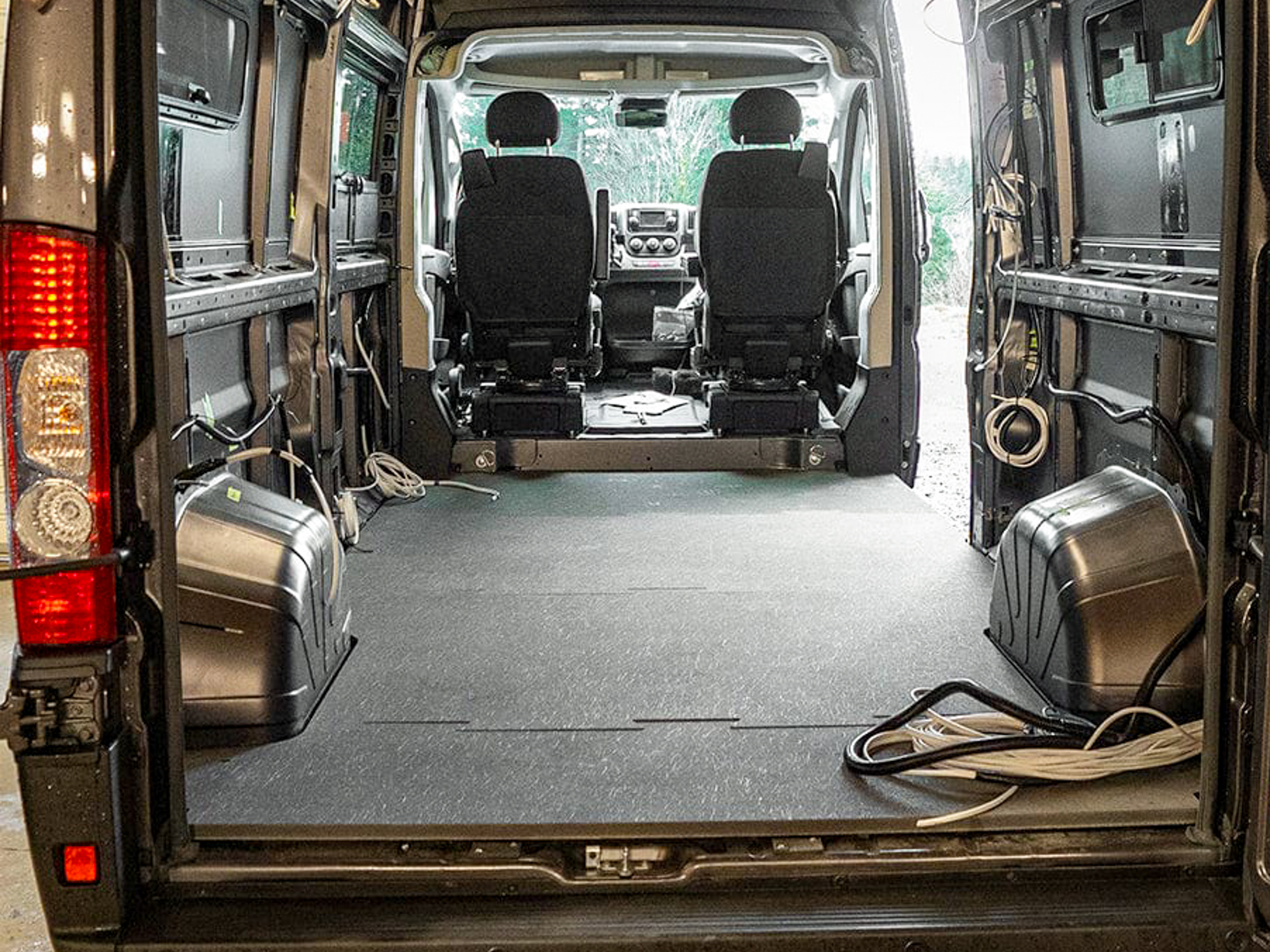 A grey composite flooring kit custom-cut to fit the specific dimensions of a Ford Transit van.