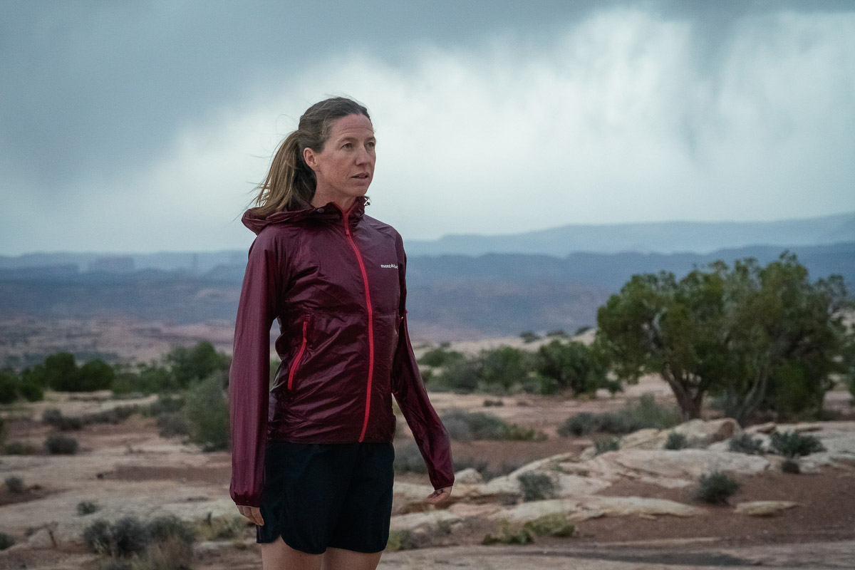 A runner wearing a blue Montbell Tachyon Hooded Jacket in a high desert environment.