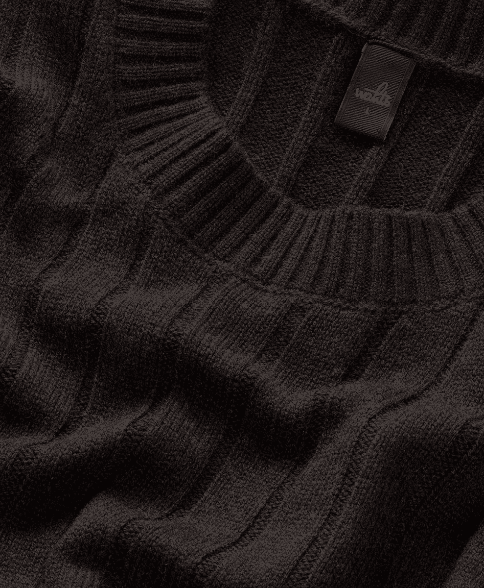 Close-up of a black ribbed knit sweater with a brand tag at the neckline.