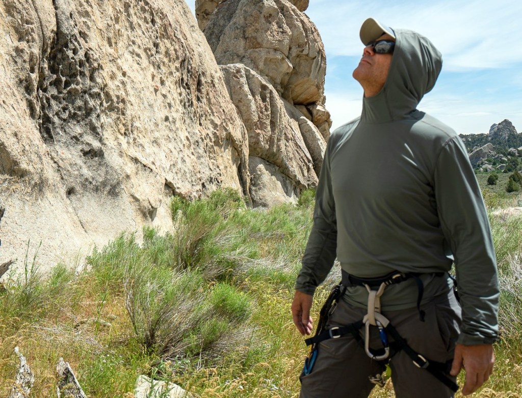 A hiker wearing the Mountain Hardwear Crater Lake Long Sleeve Hoody on a mountain trail.