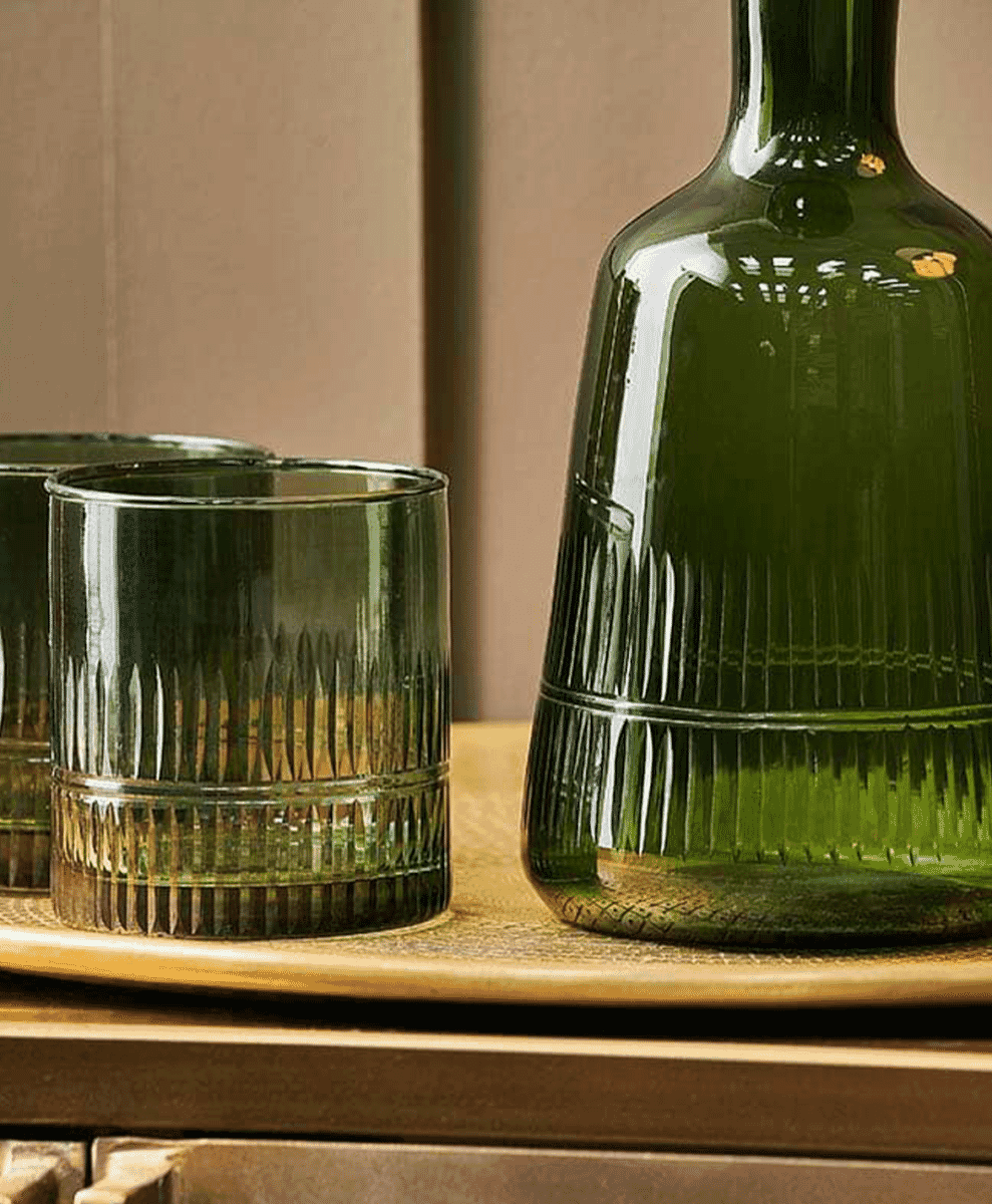 Green ribbed glass tumblers and a decanter on a wooden tray.