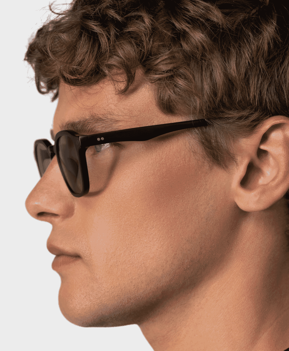 Close-up profile of black-framed sunglasses against a stark white background.