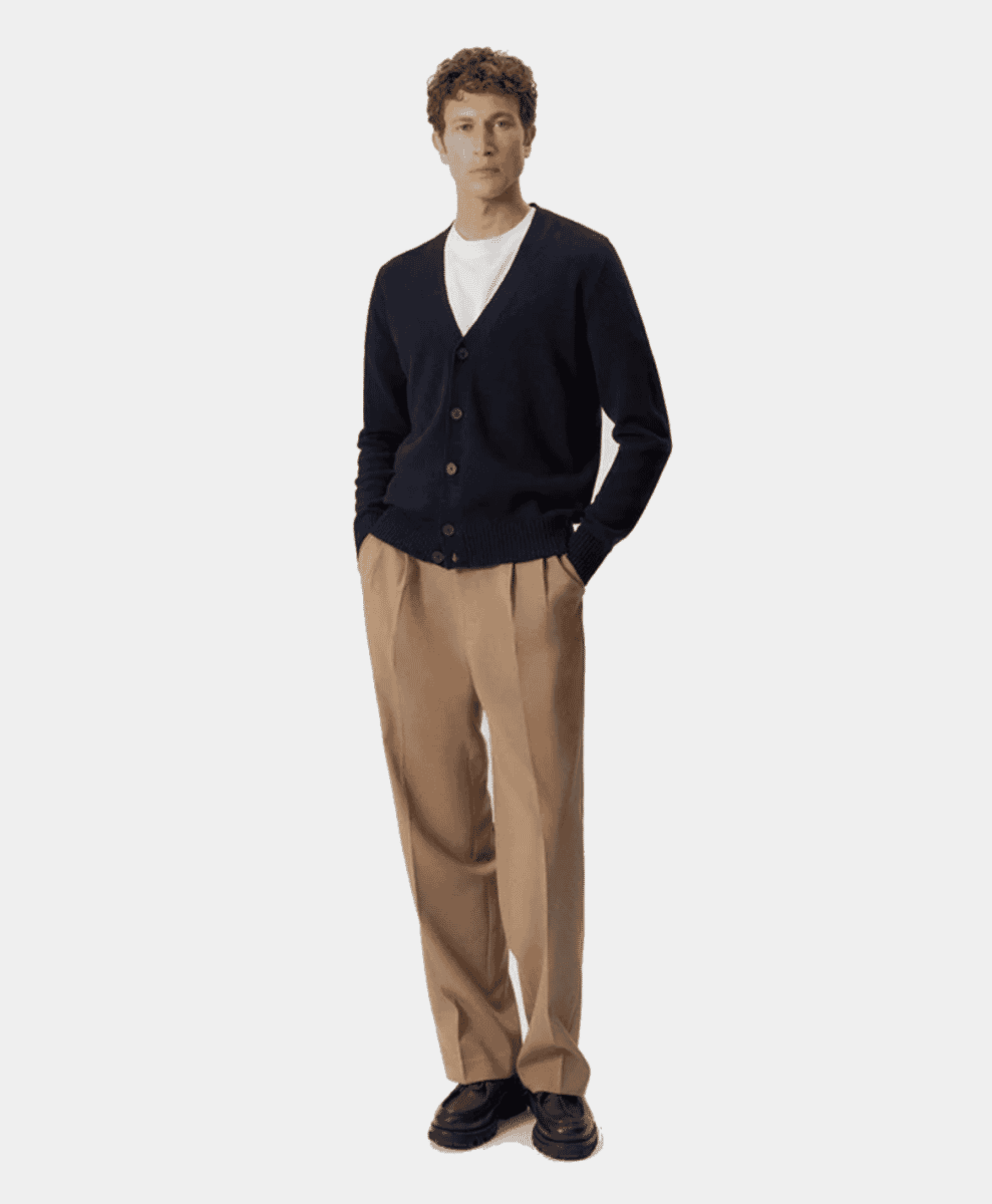 Man modeling a navy V-neck cardigan over a white t-shirt with beige pleated wide-leg trousers and loafers.