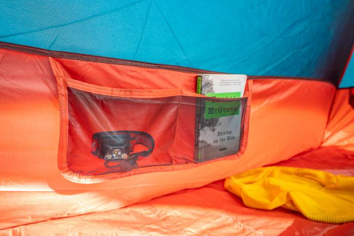 Close-up of mesh storage pockets inside a camping tent filled with small gear.