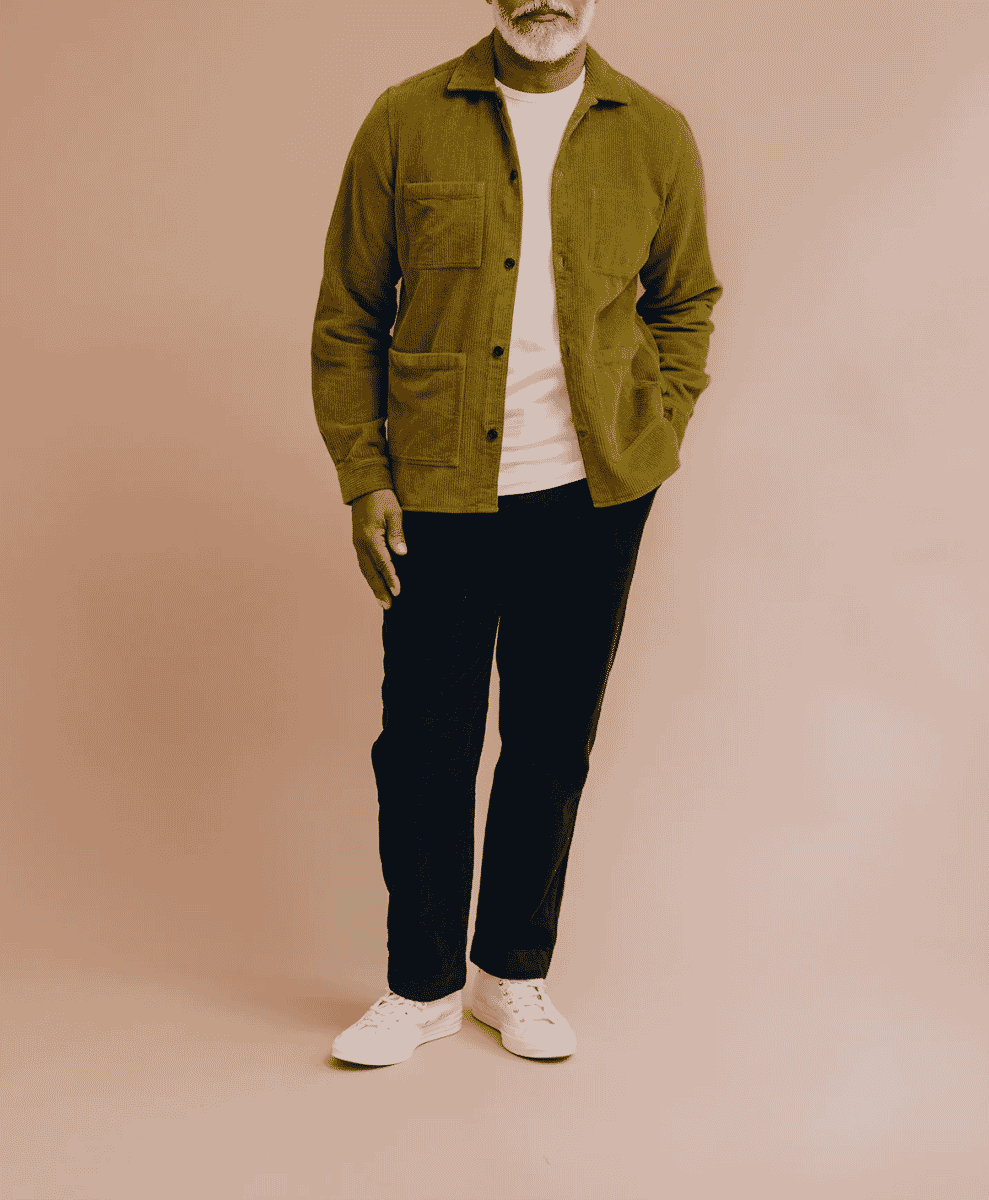 Bearded mature man in a dark corduroy jacket, dark trousers, and crisp white sneakers.