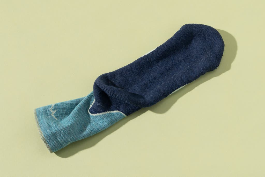 Close-up view of the dense knit and cushioned underside of a gray and blue hiking sock.