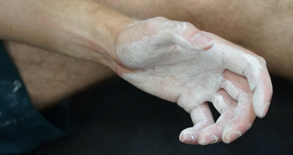 A climber's hand coated in a white layer of liquid climbing chalk