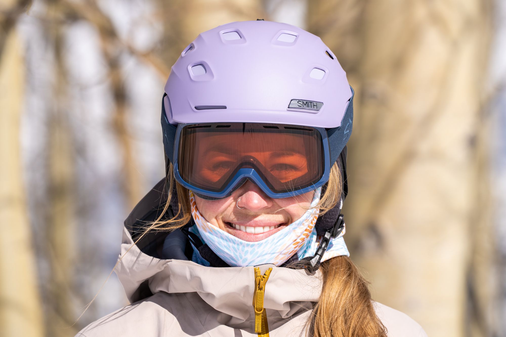 A gear tester wearing a helmet and goggles while skiing in snowy mountain conditions.
