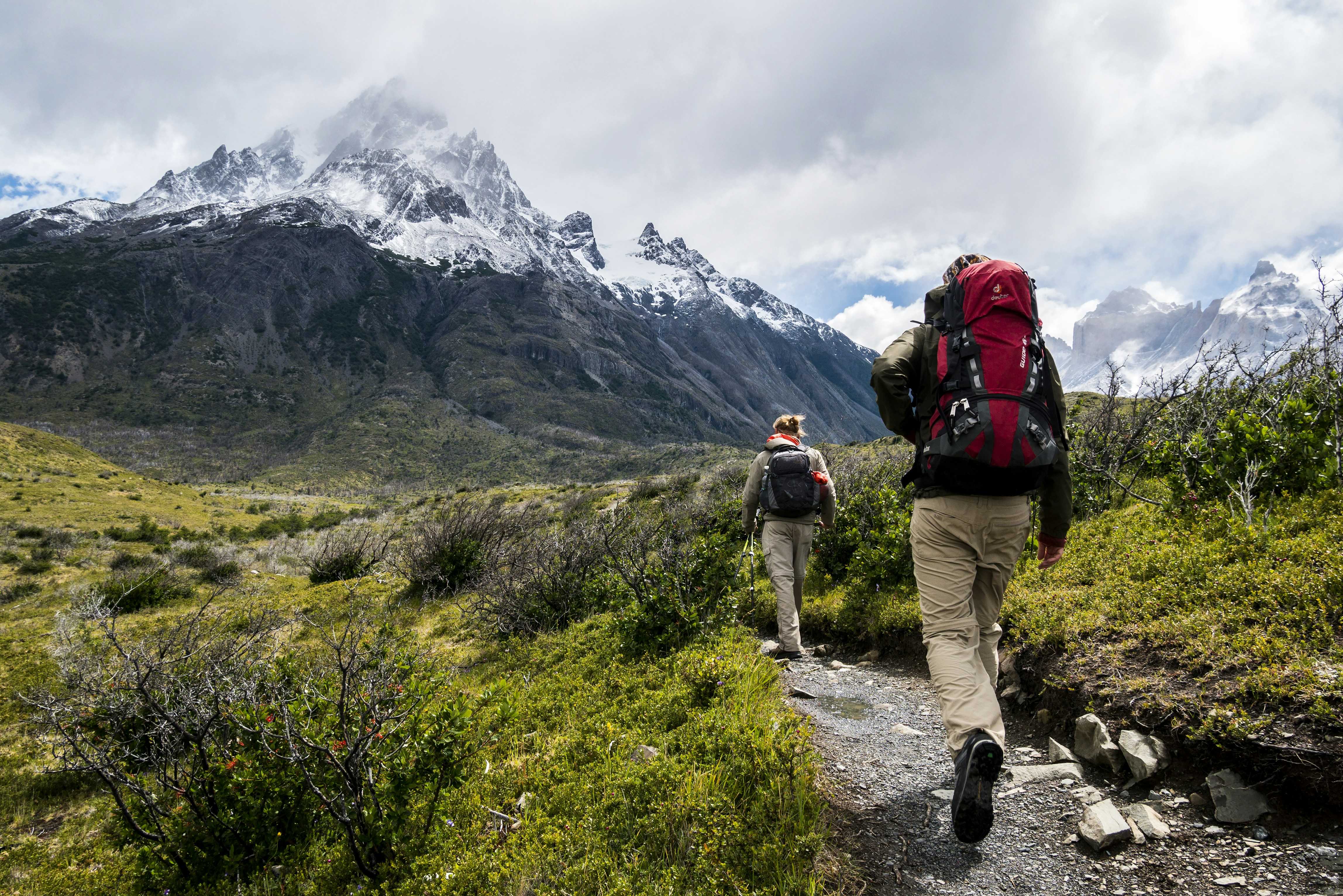 A hiker using a trekking pole to test the stability of wet ground.