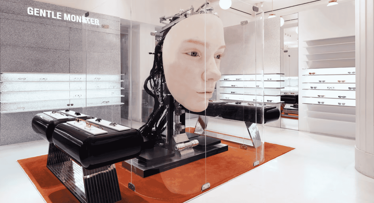 A futuristic Gentle Monster store display featuring a robotic mannequin head and eyewear in glass cases.