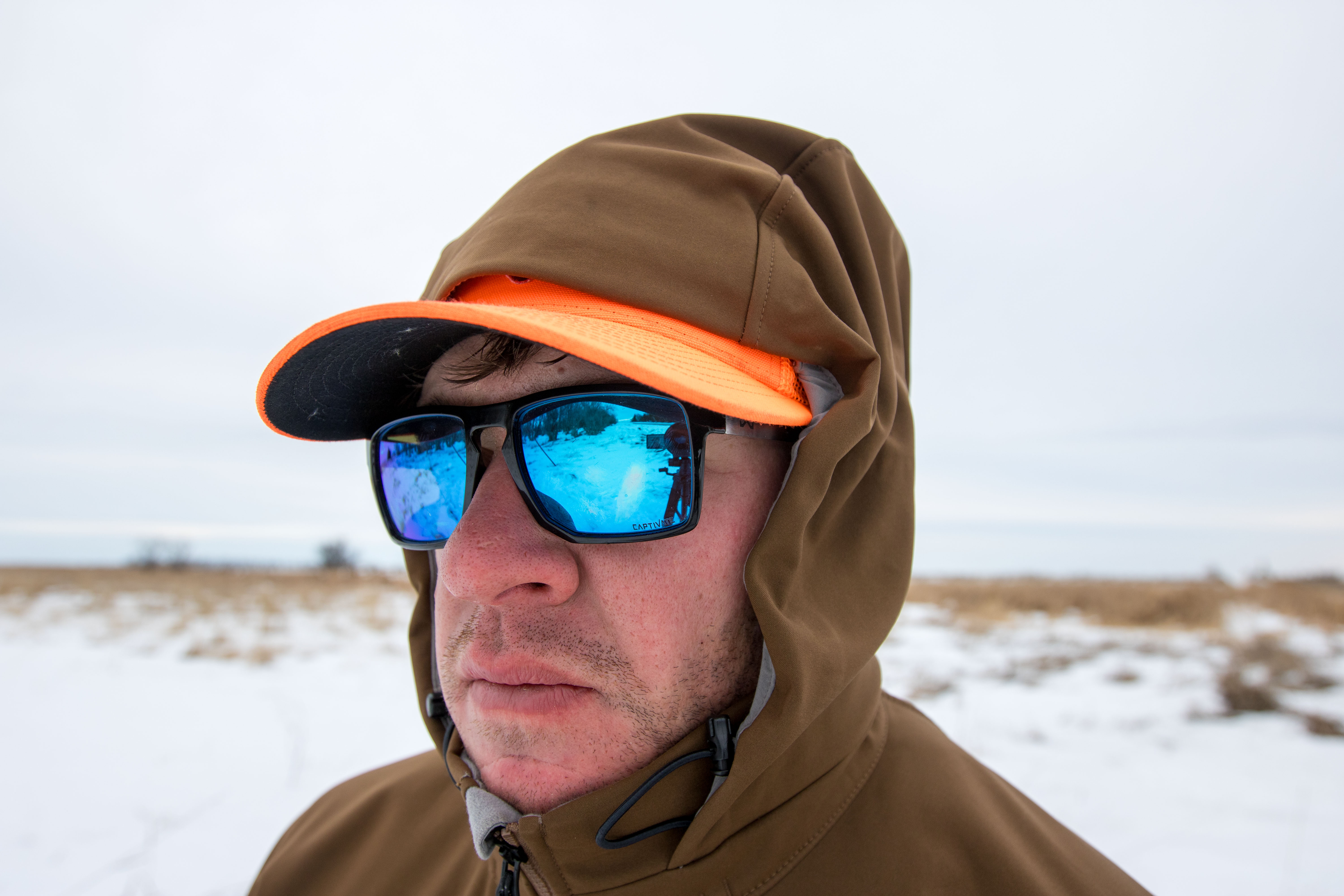 A close-up of a hunter with the SITKA Jetstream hood tightly cinched around the face for wind protection.