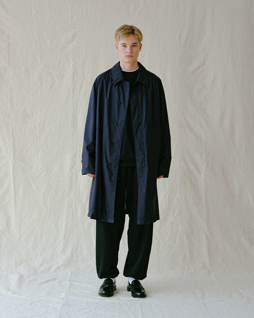 Young man in a minimalist dark navy long coat.