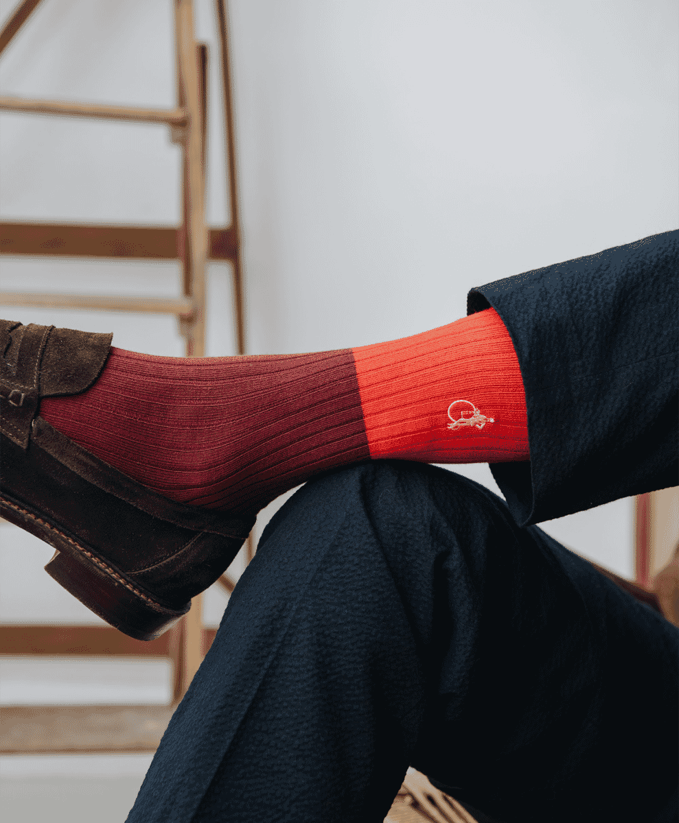 Close-up of a man's legs in burgundy socks and brown suede loafers.