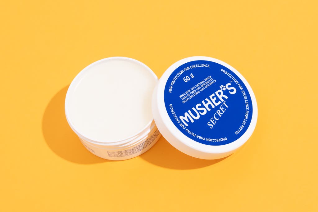 A round container of Musher's Secret paw wax on a white background.