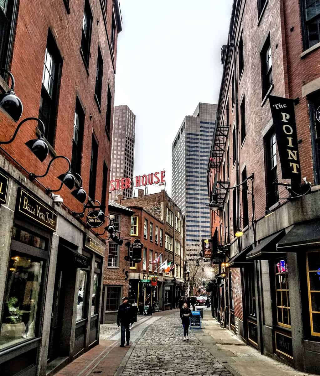 Snow-covered cobblestone street lined with historic brick buildings in Boston.