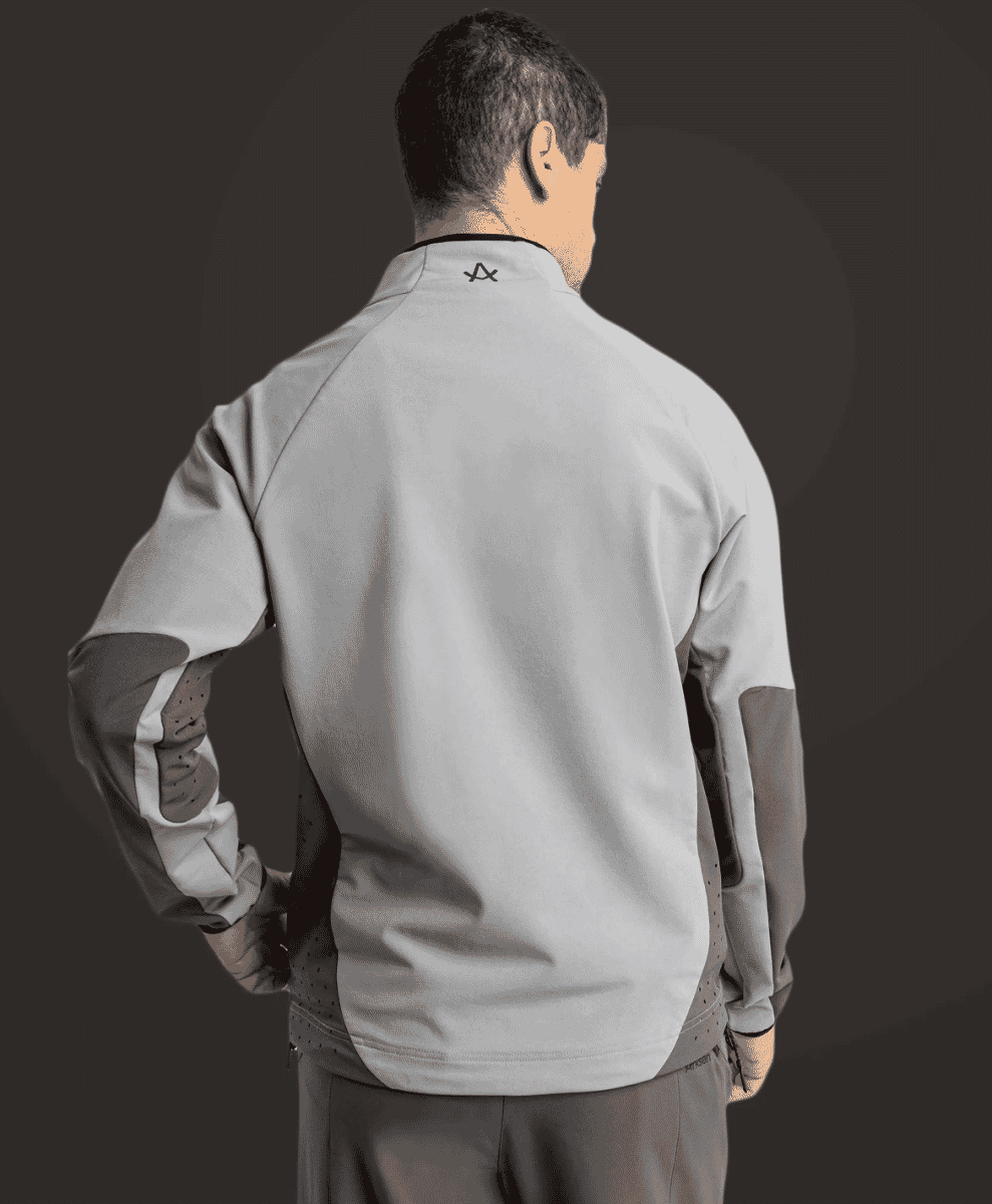 Rear view of a man wearing a light gray and dark gray athletic technical jacket.