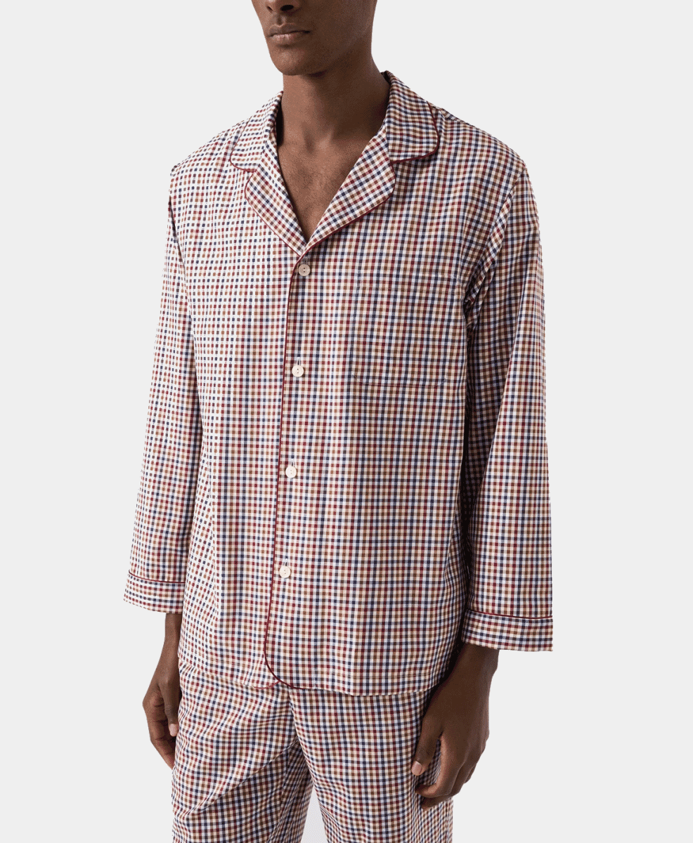 A man modeling a red, blue, and beige gingham-patterned pajama set.