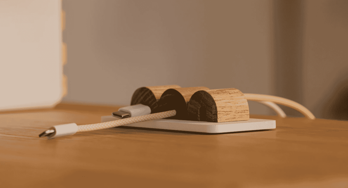 A wooden OAKYWOOD magnetic cable organizer with USB-C cables arranged on a desk.