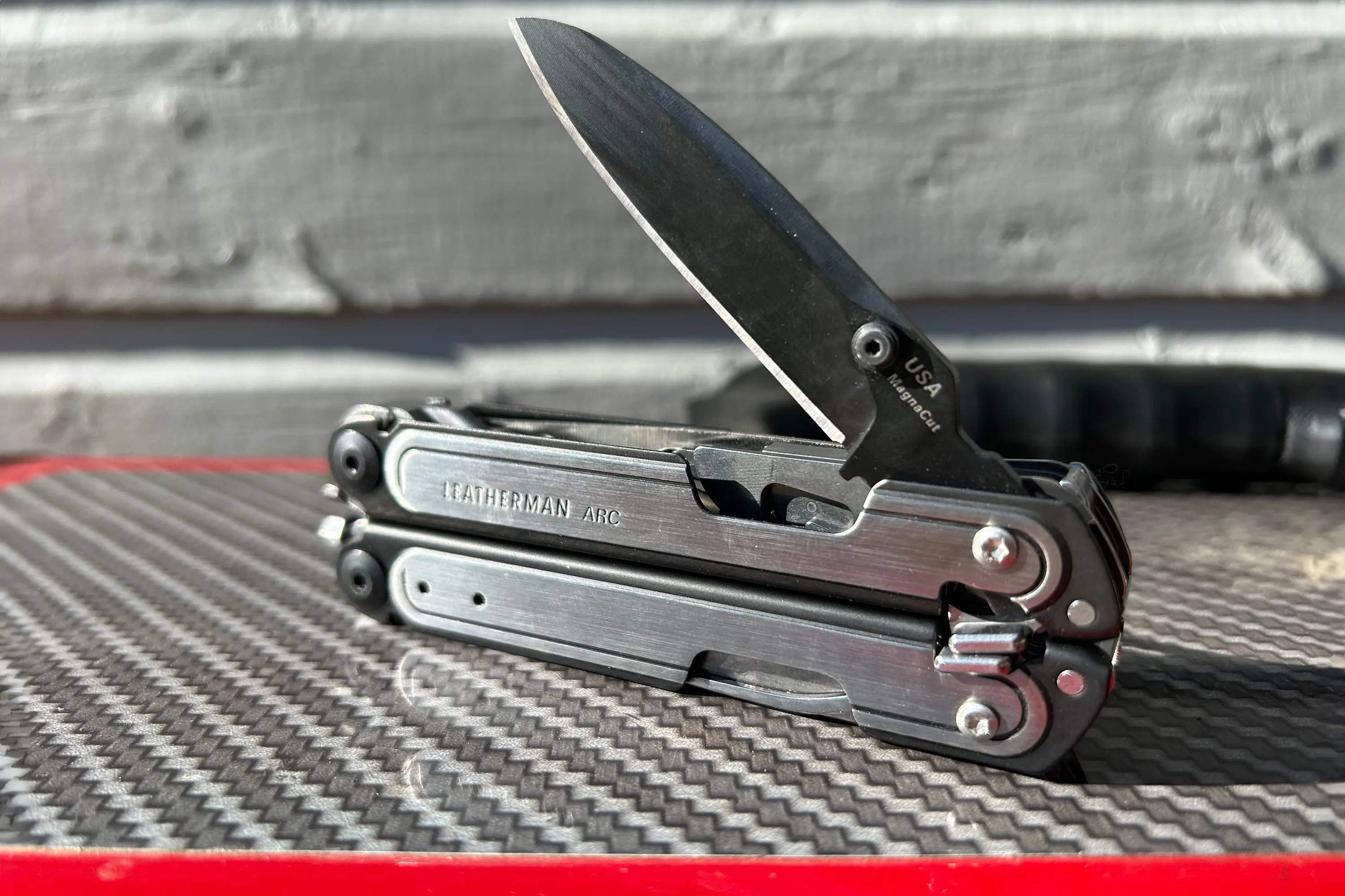 Close-up of the Leatherman Arc multitool showing the specialized MagnaCut steel logo on the blade.