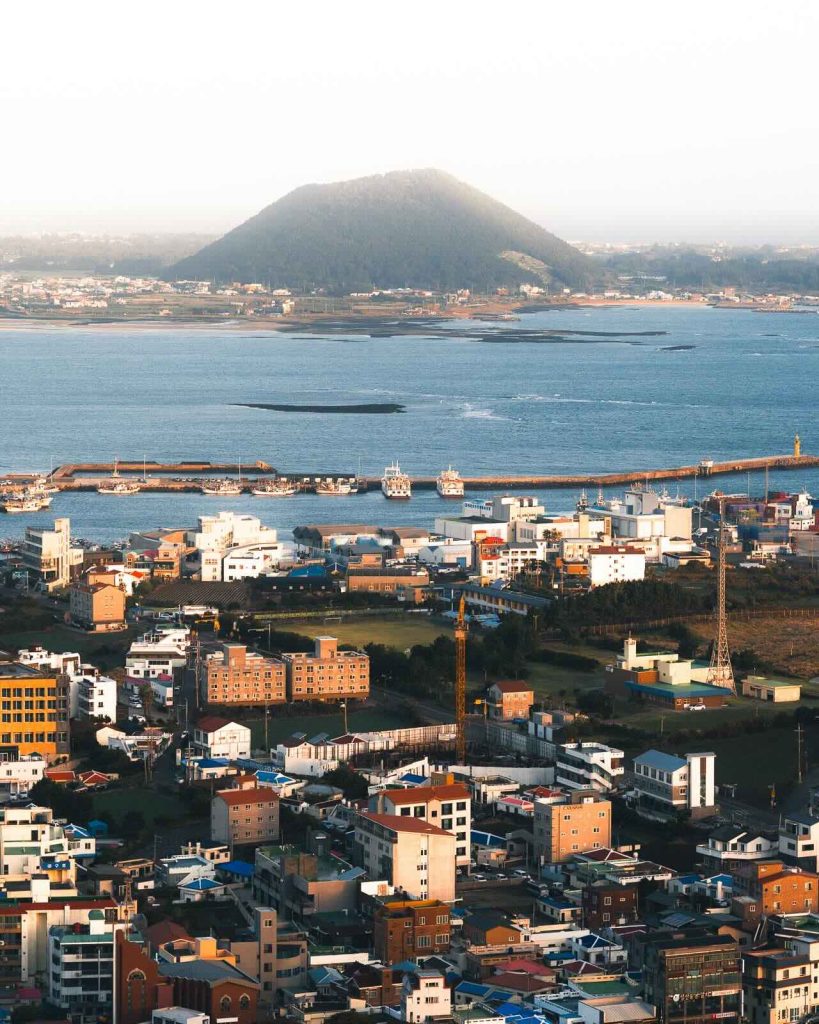 Aerial view of the lush green crater of Seongsan Ilchulbong meeting the ocean.