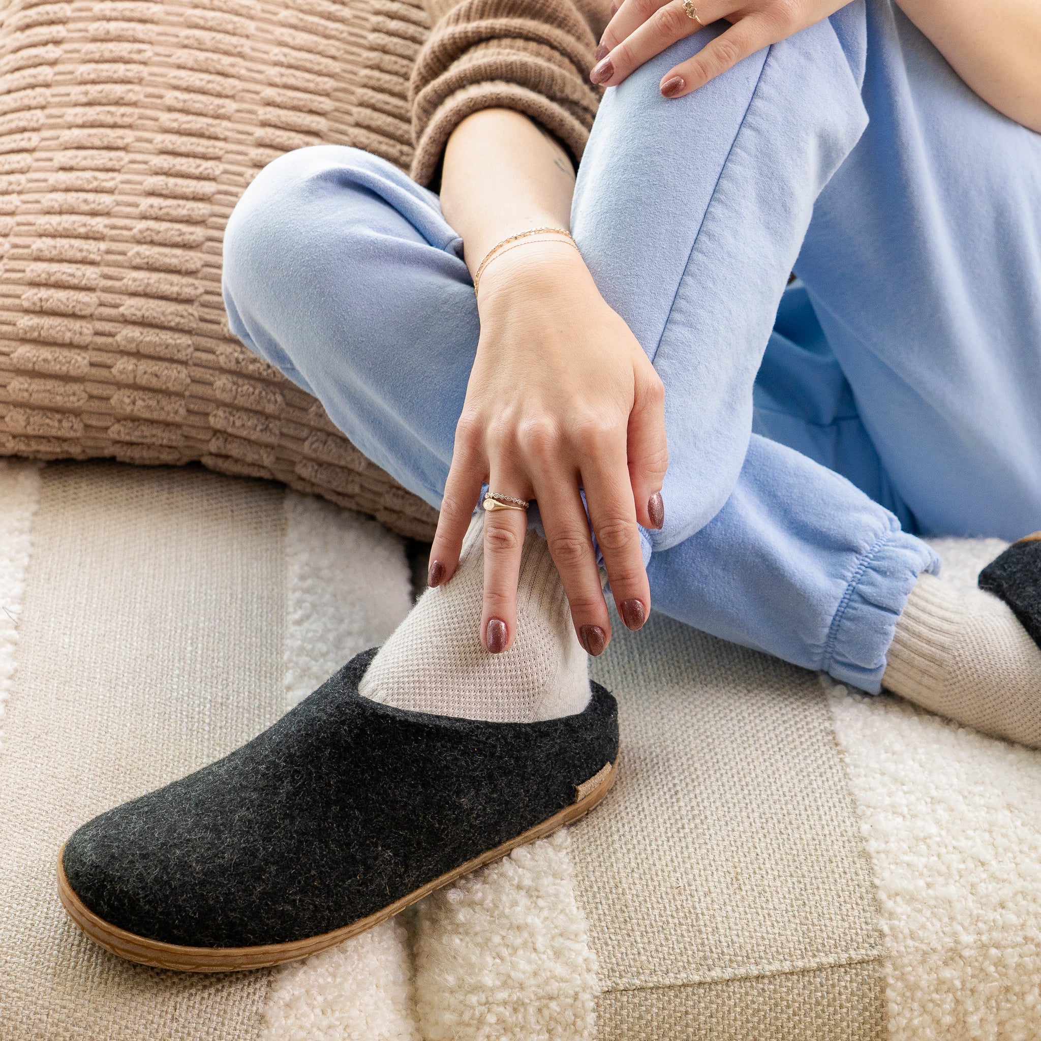 A person wearing grey felted-wool Glerups slippers with a black rubber sole.