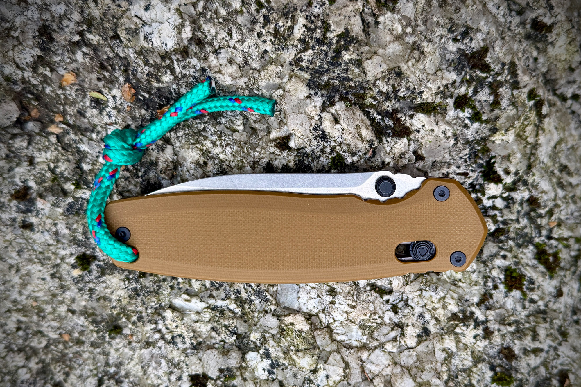 The Kershaw Broadside folded on a grey stone surface with a green paracord lanyard attached.