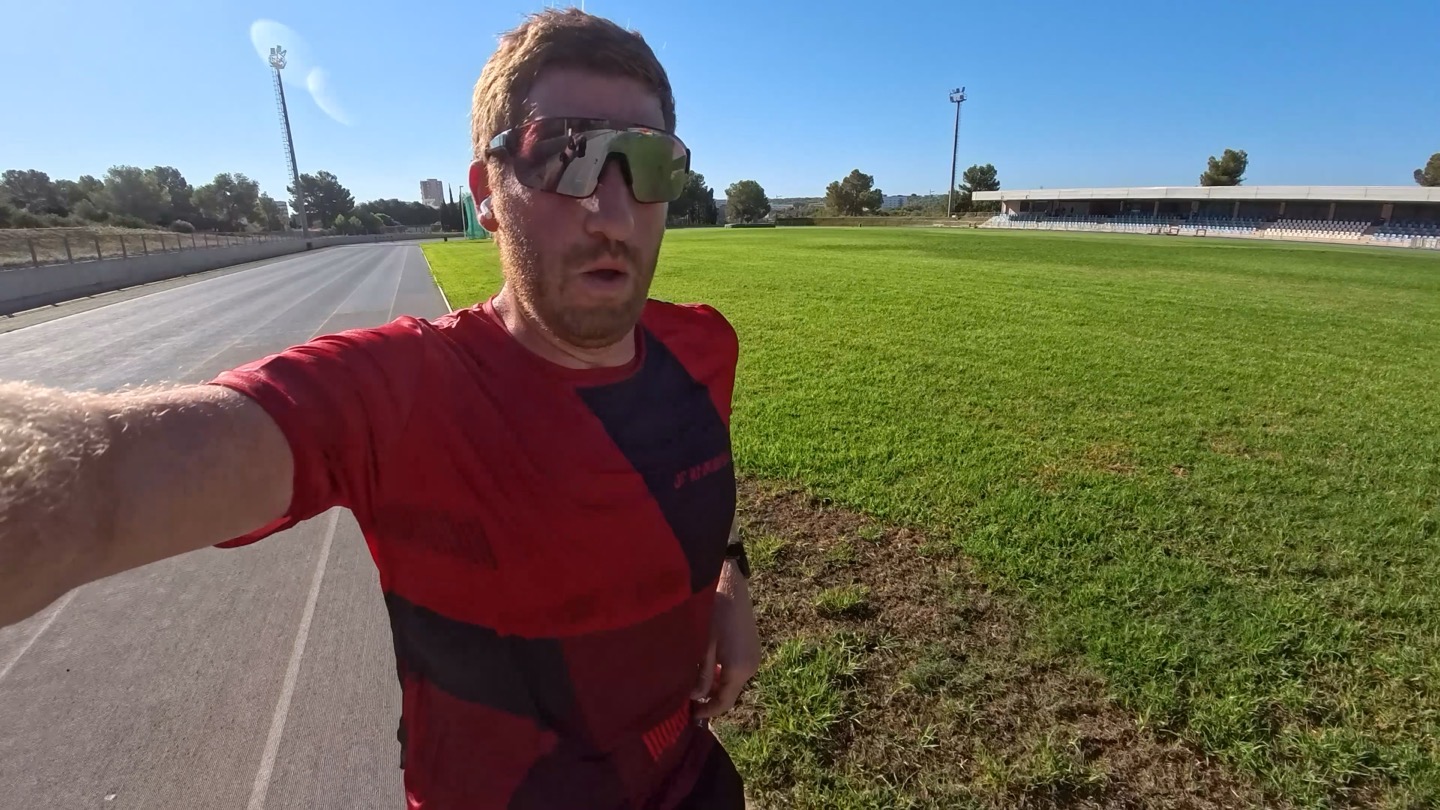 A person running on an outdoor track wearing AirPods Pro 3.