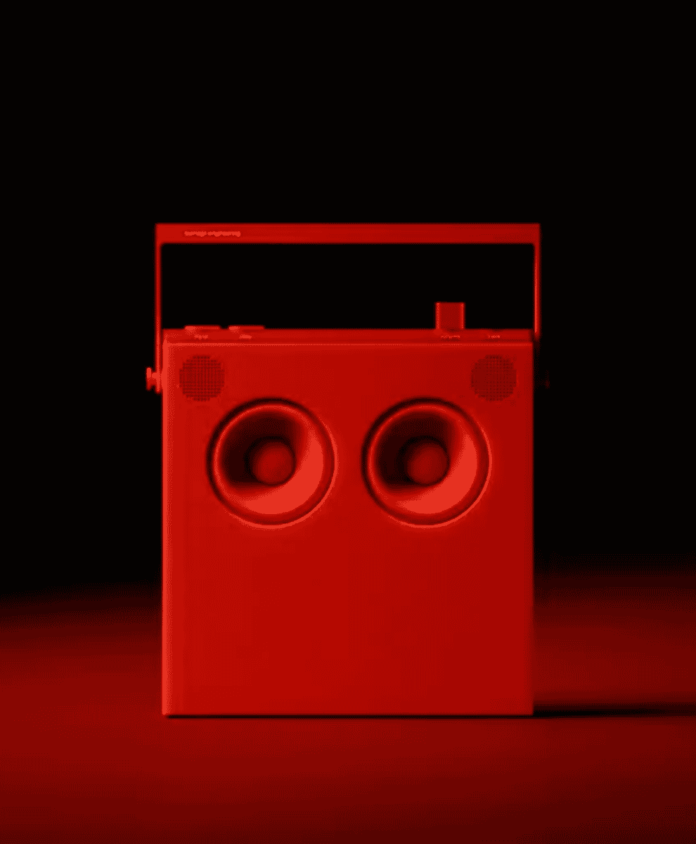 A vibrant red vintage-style portable speaker with dual drivers against a dark background.