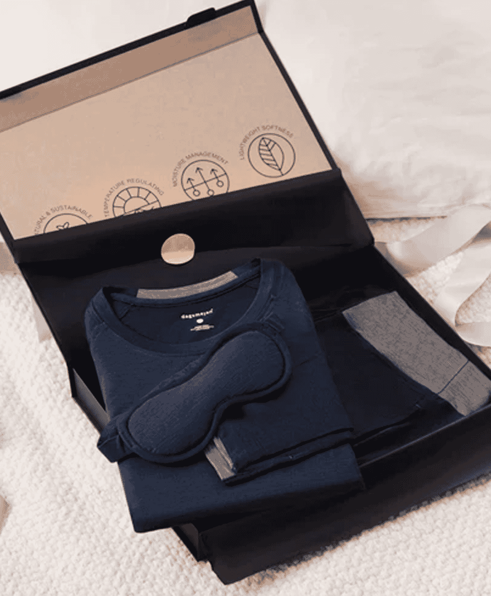A navy Dagsmejan NATTWARM pajama set neatly folded in a black gift box.