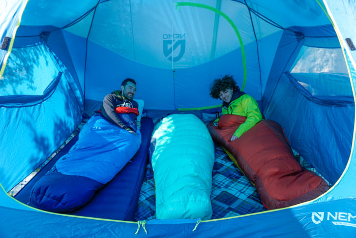 Campers sitting inside a NEMO Aurora Highrise tent with high ceilings.