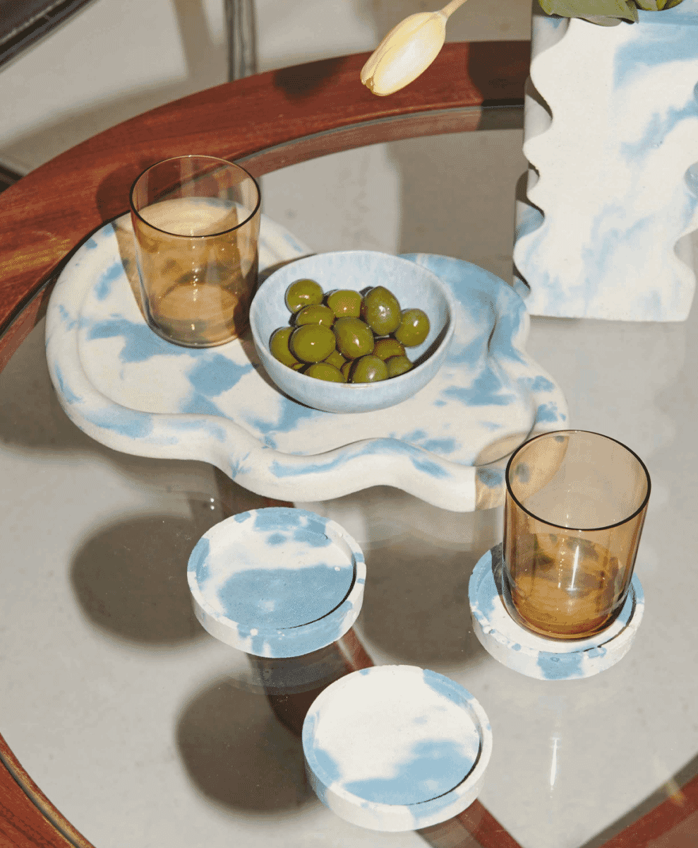 A blue and white marbled ceramic tray styled with amber glasses and coasters on a table.