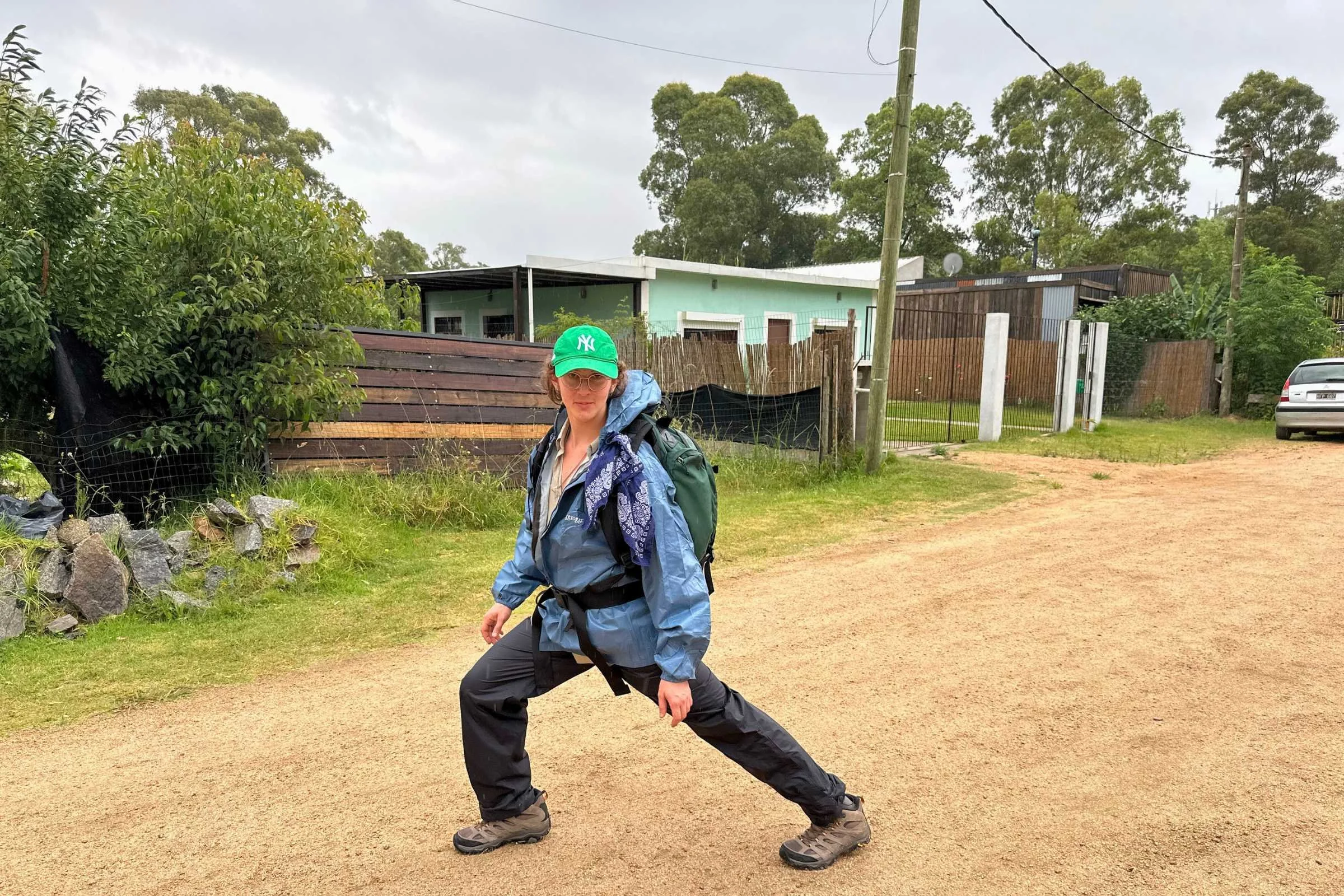 A hiker performing a half-lunge while wearing black Marmot rain pants.
