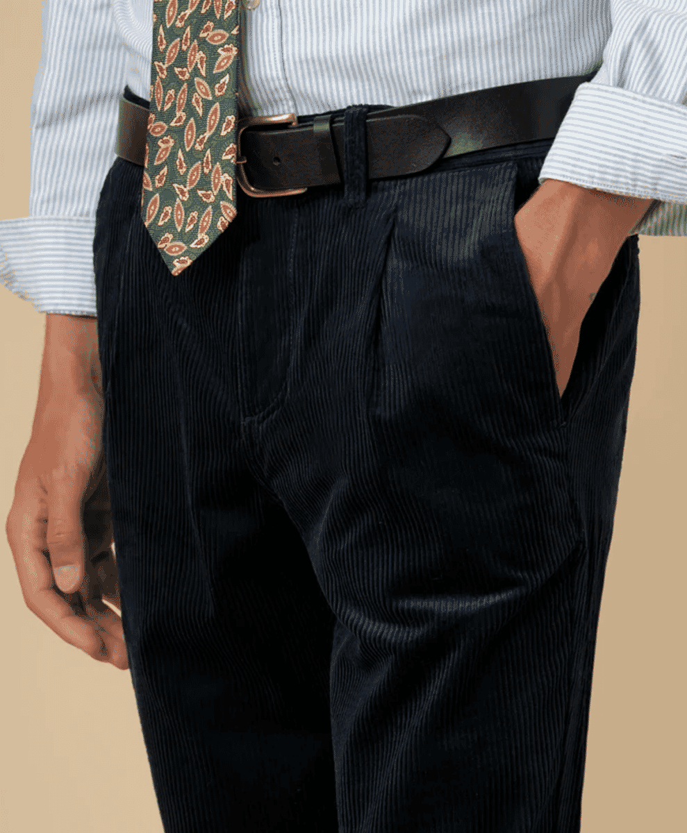 Man wearing dark pleated corduroy trousers with a dress shirt and patterned tie.
