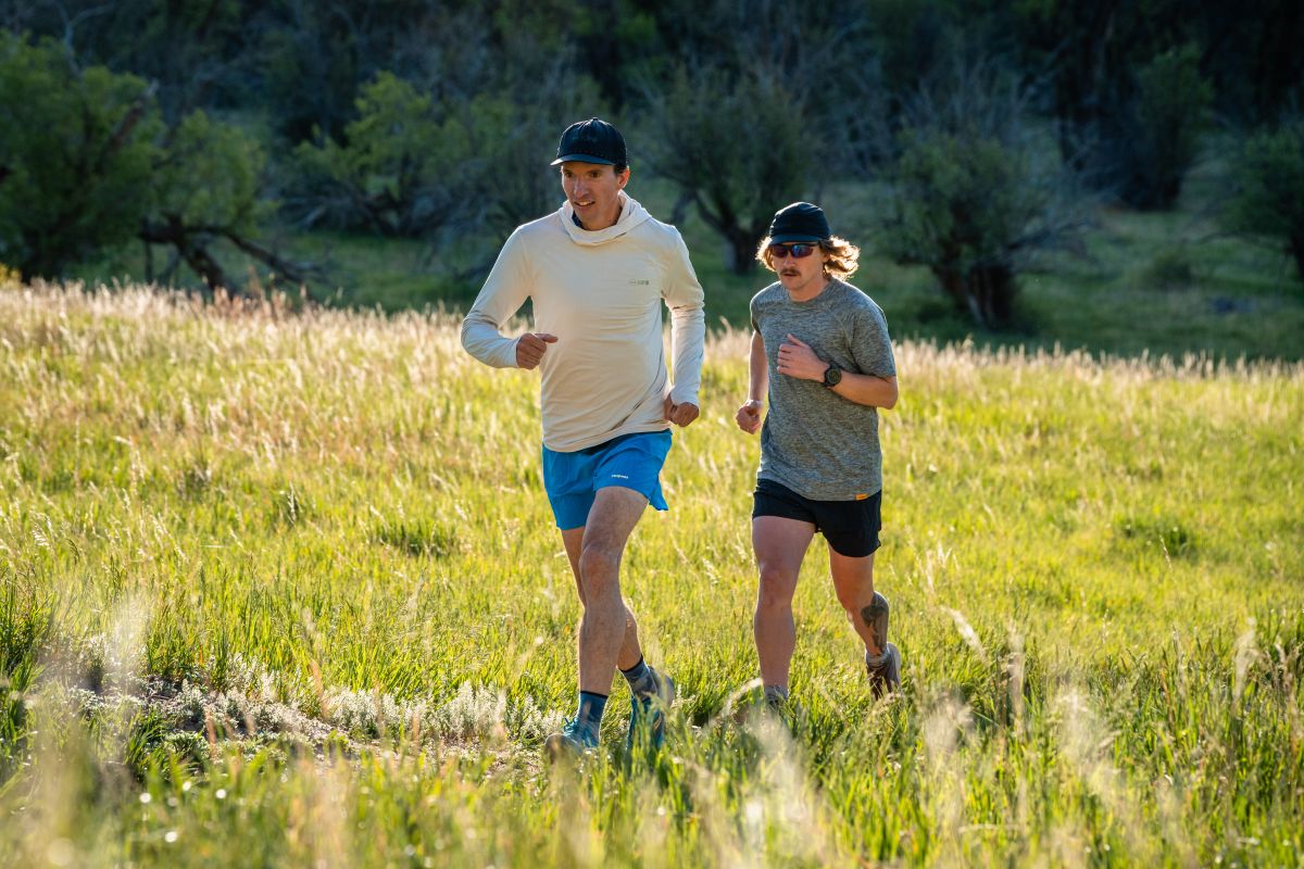 Two trail runners navigating a scenic high-altitude trail in Colorado.