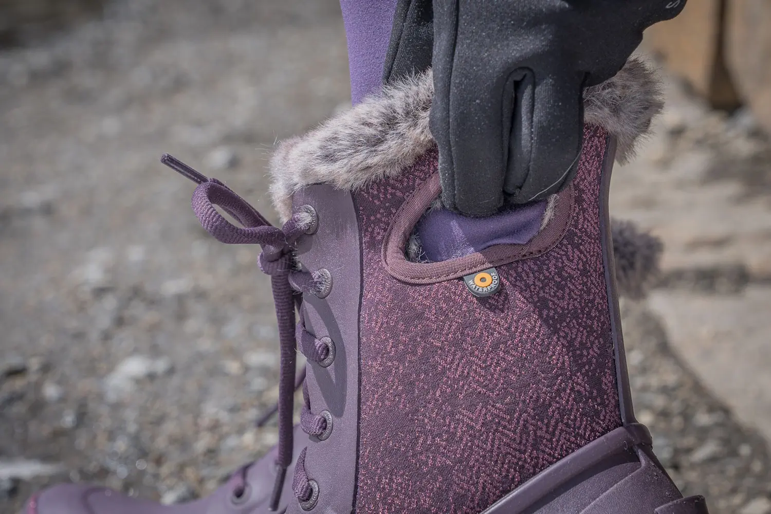 A close-up of a hand using the integrated side handle to pull on a Bogs winter boot.