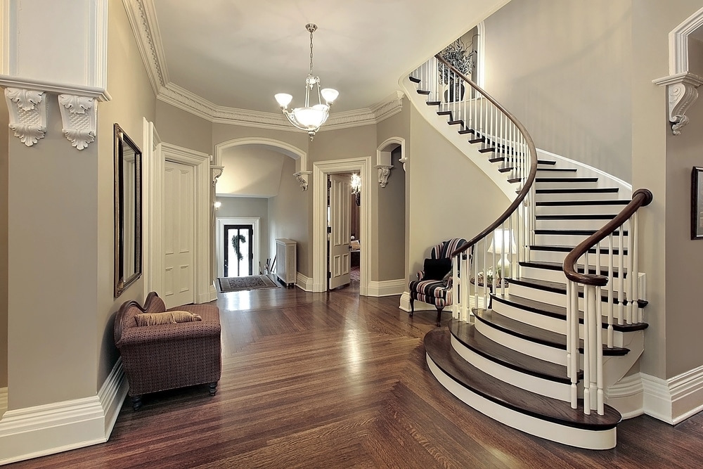 Elegant hallway with a curved staircase, hardwood floors, and classic furnishings.
