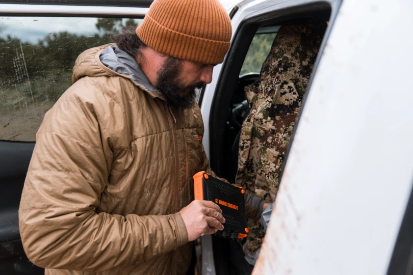 A hunter holding the compact Poseidon XL while preparing gear next to a truck.