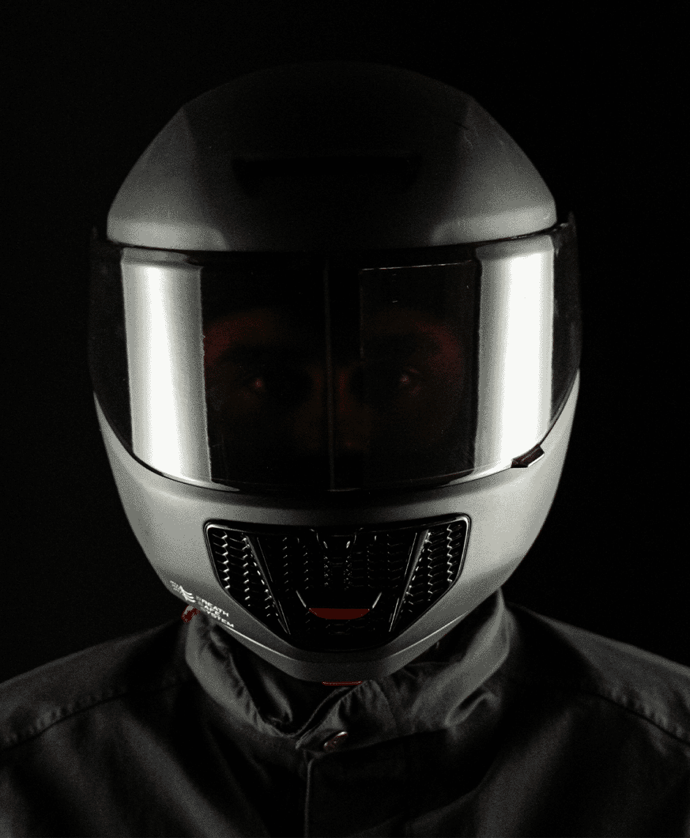 Person in a silver full-face helmet with a reflective visor and black air grille
