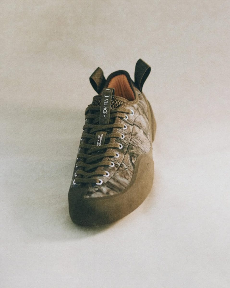 Climbing shoe featuring a camouflage pattern and olive green laces with Village branding.