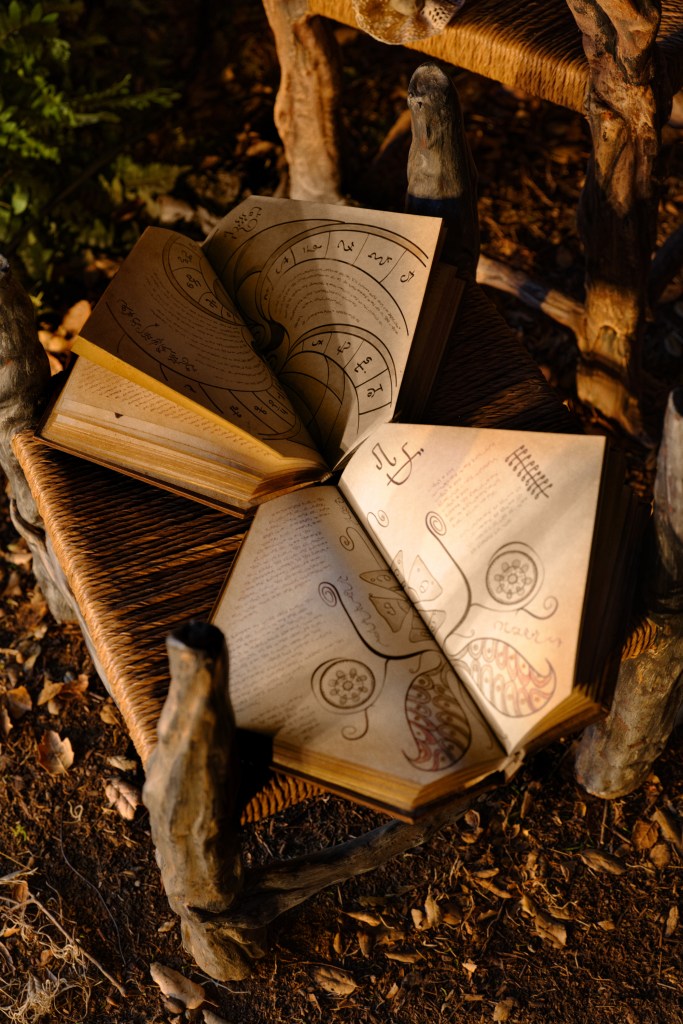 A close-up of the sacred Grimmerie spellbook on a rustic wooden table.