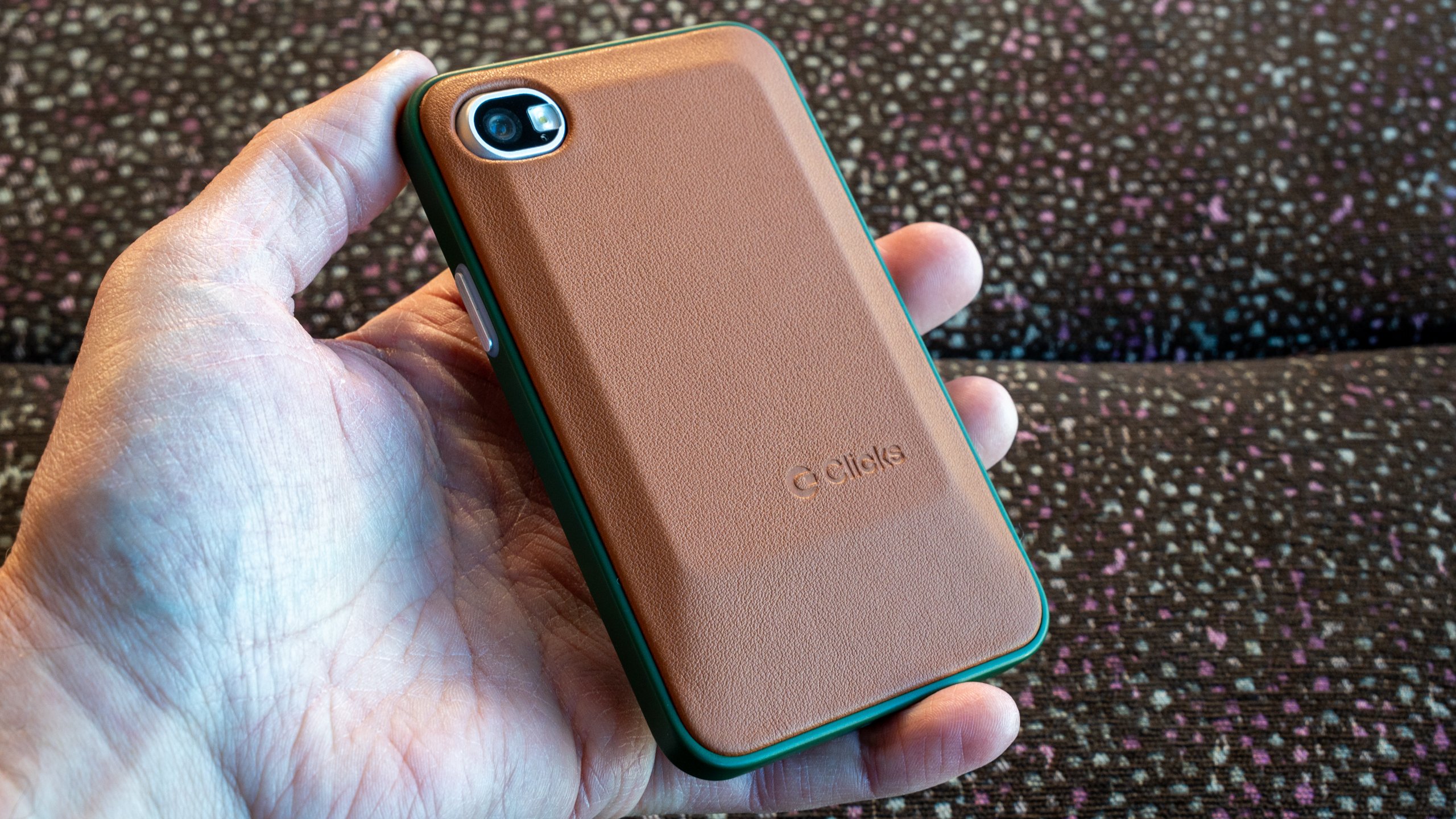 A person holding the green Clover model of the Clicks Communicator in one hand.