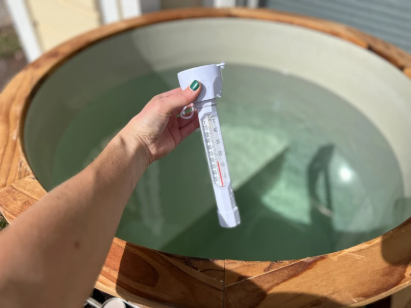 A thermometer measuring the water temperature inside a Redwood Outdoors Alaskan Cold Plunge Tub.